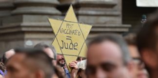 A protester holds a yellow star reading “Not Vaccinated = Jew” as protesters take part in a demonstration in Milan, Italy, July 24, 2021
