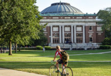 A student bikes across a college campus