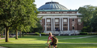 A student bikes across a college campus
