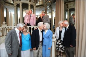 Five elderly couples all kissing at once