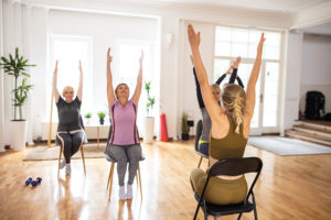 Yoga instructor having class with women on chairs