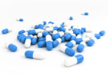 White and blue capsules spilled over white background