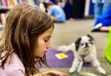 A child reads to a dog through the Mitzvah Mutts program