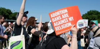 A protester holds a sign saying “Abortion bans are against my religion”