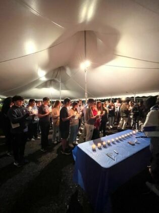 Teens holding candles sing a prayer