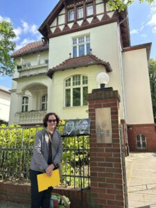 Judy Gartner in Berlin next to plaques of her grandparents 