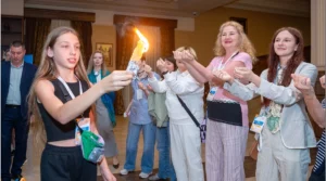 A girl holds a Havdalah candle while other women around her look at the reflection of the light in their nails