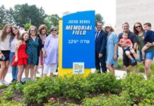 Area Day Schools Welcome in the Year With New Programs, Staff and More Beth Tfiloh community members and building partners stand next to a sign that says "Jacob Benus Memorial Field"
