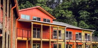 Photo of a reddish-brown three-story building that resembles a long house.