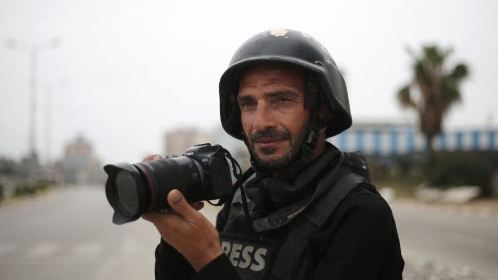 A journalist wearing a helmet and holding a camera