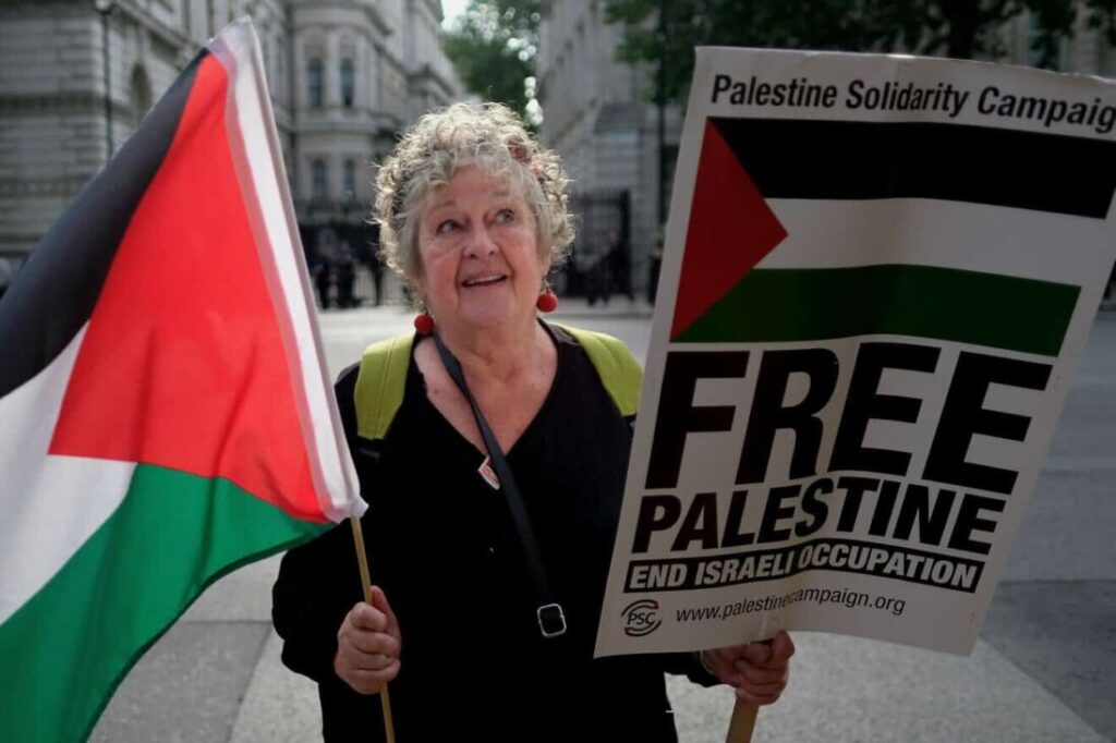 A woman holding a flag and a sign.