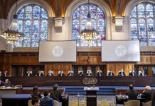 Opinion: To End the Criminal Case Against Israel, Sanction South Africa A large, ornate room with two large monitors.