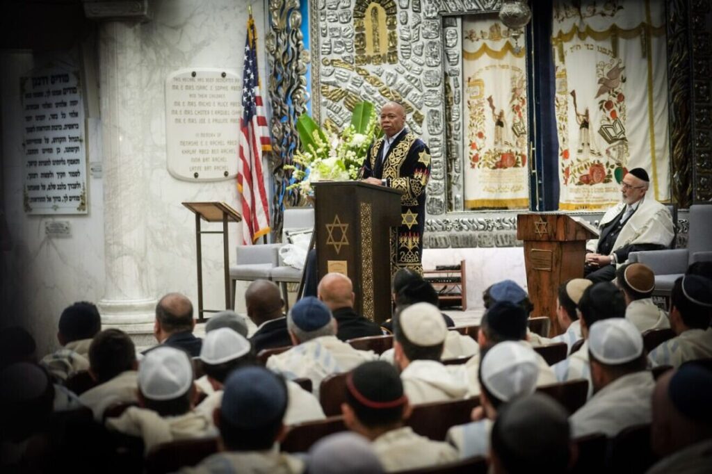 A man standing at a podium and addressing a congregation.