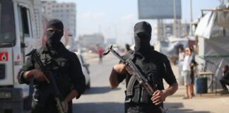 Two masked men wearing black and holding guns.