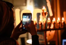 A person taking a photo of a Chanukah menorah on a cell phone.