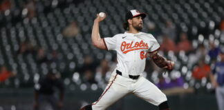 A man wearing a baseball uniform about to throw a ball.