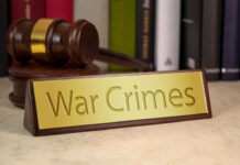 Gavel and law book with sign and war crimes on a wooden table