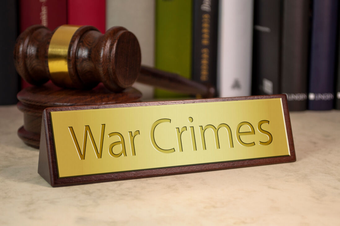 Gavel and law book with sign and war crimes on a wooden table